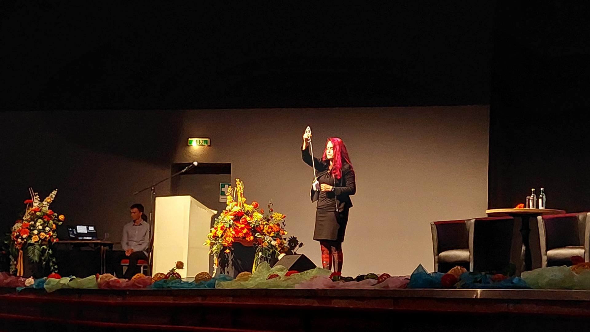 Infoveranstaltung mit Prof. Dr. Michèle Heurs eine Frau mit violetten Haaren steht auf einer Bühne und präsentiert ein Experiment