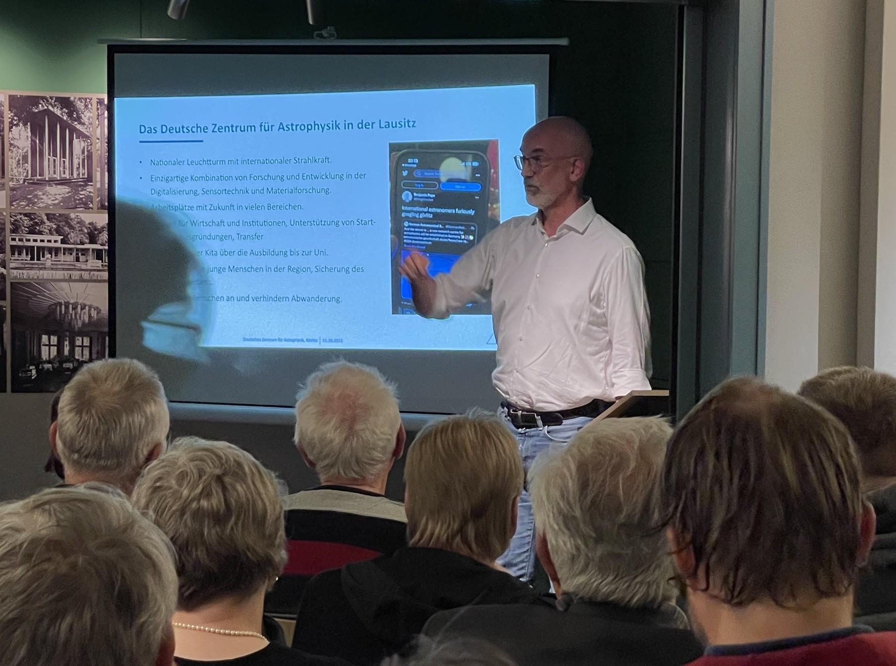 Infoveranstaltung mit Prof. Dr. Christian Stegmann ein Mann mit weißen Haaren und Brille steht vor einer Präsentation und spricht zu einem Publikum