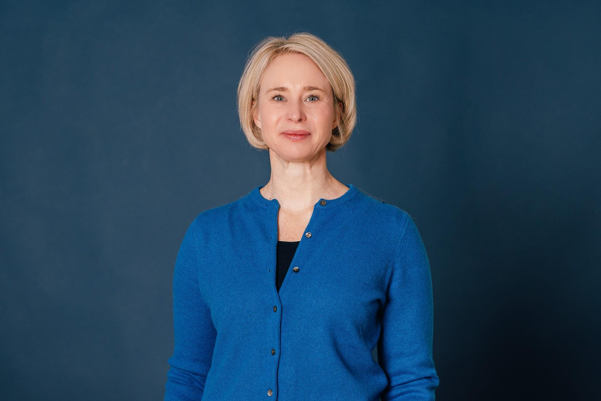 Frau mit halblangen blonden Haaren, schaut freundlich in Kamera 